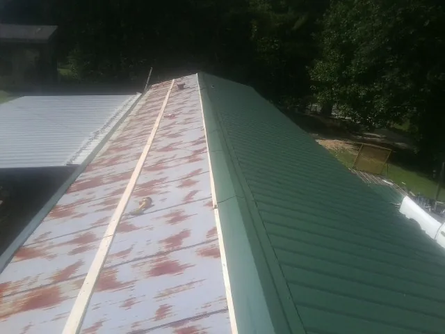 Old rusted panels beside newly installed green metal roofing — Wind Damage Roof Repair by Roofing Brothers in Taylor