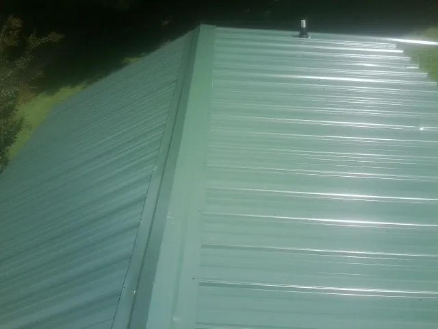 New green metal panels meeting at the ridge of a roof — Flat Roof Repair work by our crew in Taylor