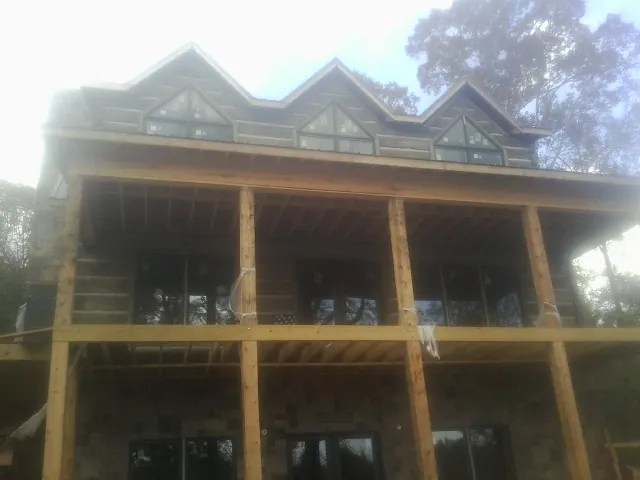 Dormers and porch framing on a large log home under construction — Roof Coating work by our crew in Taylor